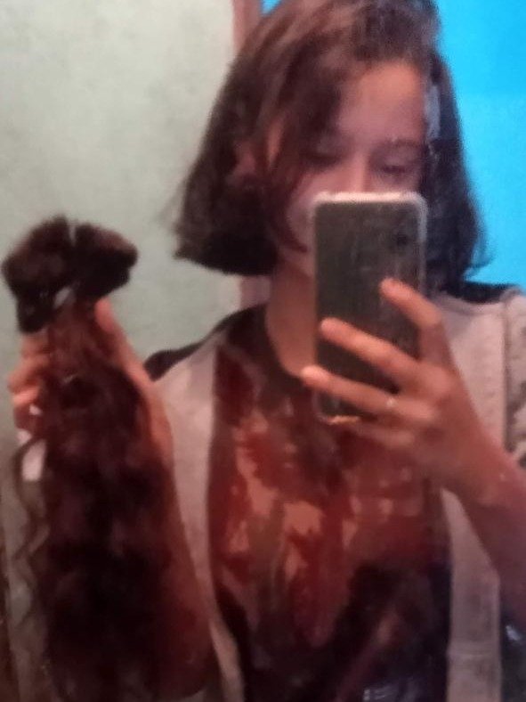 Renata aos 18 anos segurando o cabelo cortado
